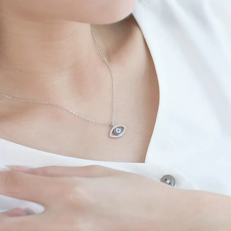 Silver evil eye necklace with blue crystal, worn for spiritual protection and positive energy