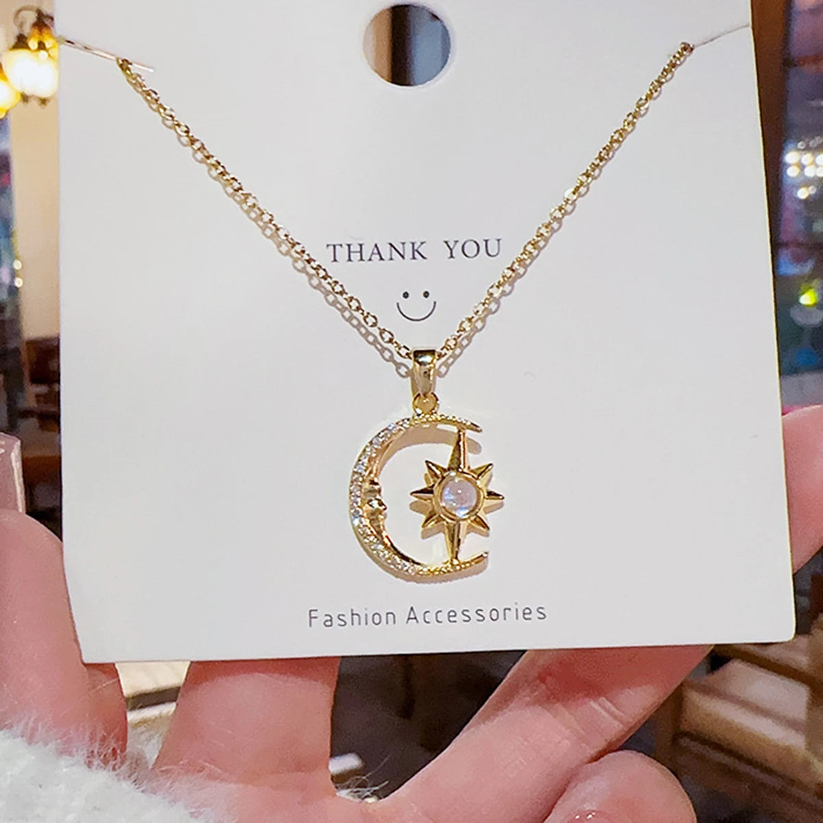Gold necklace with moon and star pendant on a 'Thank You' card