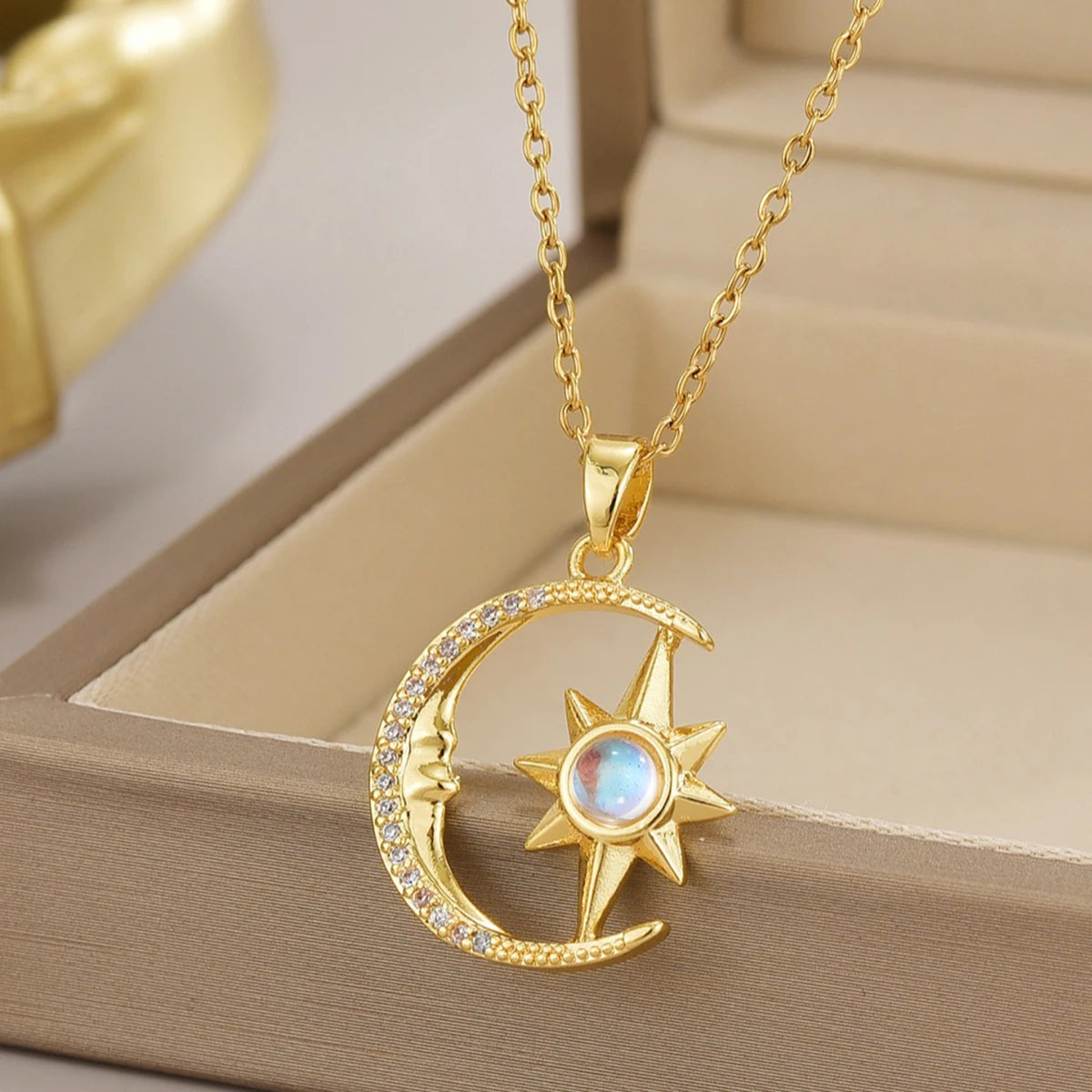 Gold necklace with moon and star pendant on a beige surface