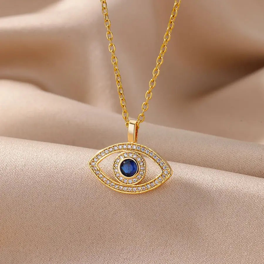 Gold necklace with an eye-shaped pendant featuring a blue gemstone on a beige fabric background